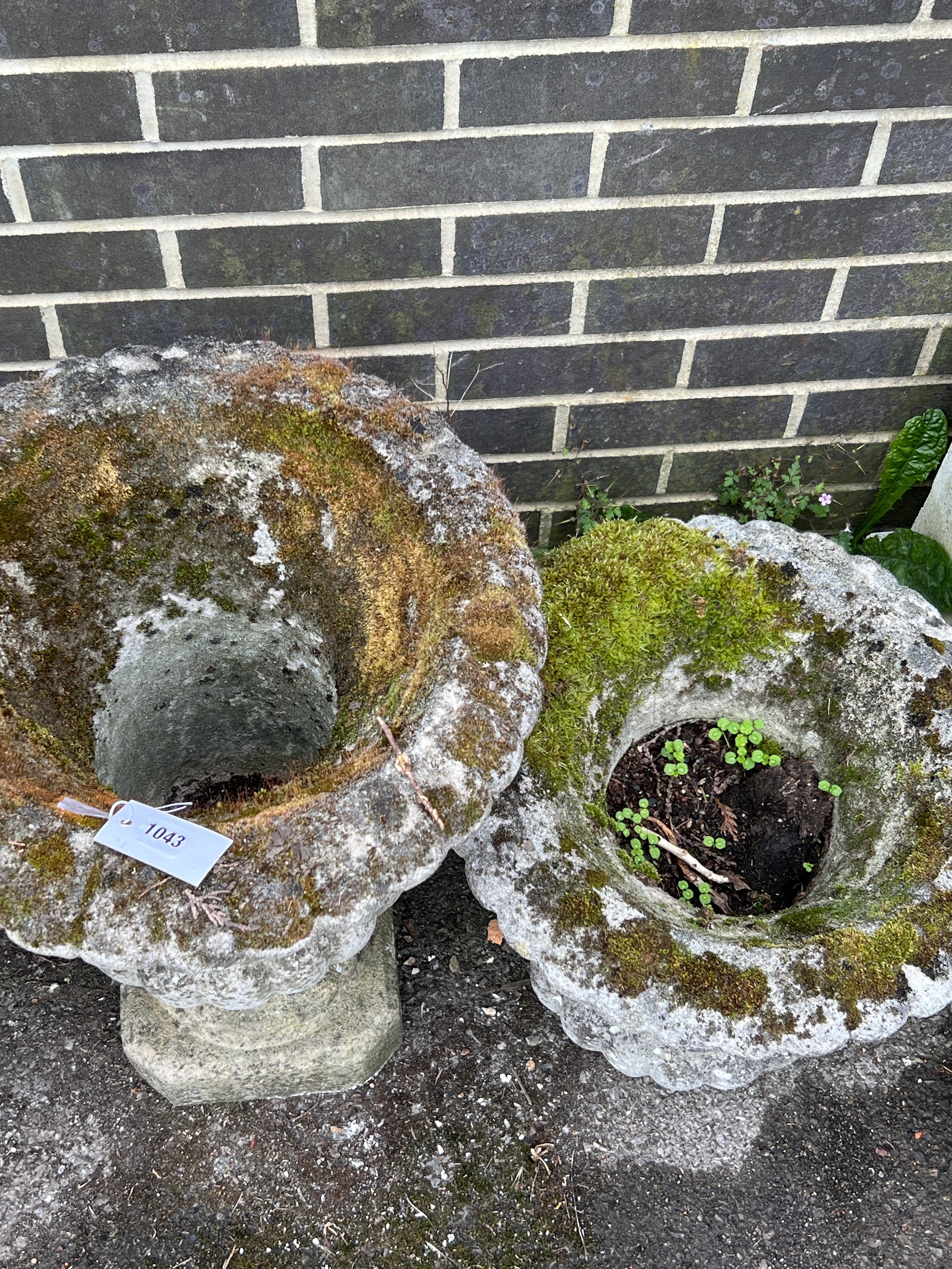 A pair of reconstituted stone circular campana garden urns, one lacks base, larger diameter 44cm, height 64cm